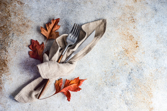 Autumnal cutlery set in wrapped in a napkin with autumn leaves