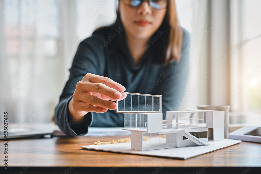 Poster undergraduate architecture students work on models of the modern box glass house. holding the part o