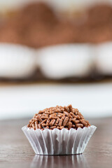 Brigadeiro doce brasileiro isolado na frente com brigadeiros ao fundo desfocados.