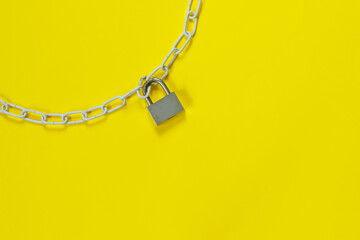 Fototapeta na wymiar The padlock and chains on yellow background. Flat lay, top view with copy space for text.