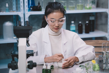 Young researcher is grind the powdered research into grinding cup in the laboratory. women are...