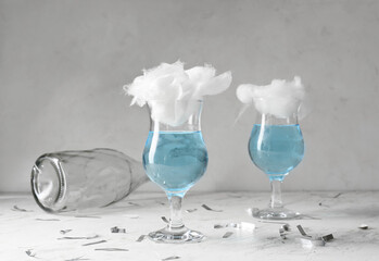 Glasses with delicious cotton candy cocktail and confetti on light background