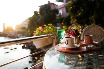 Turkish coffee cups served outside with water flowers and delight dessert in romantic setup on glass table