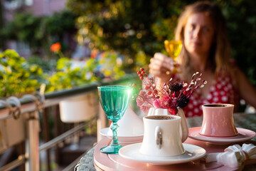young woman enjoying a cup of Turkish coffee served outside with water flowers and delight dessert in romantic setup on glass table