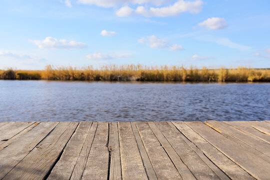 Closeup view of wooden pier near river on sunny autumn day © Pixel-Shot