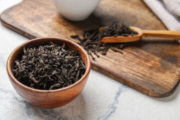 Wooden bowl with dry tea leaves on table