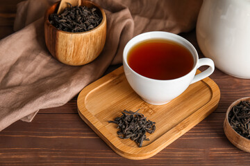 Cup of hot black tea on wooden table
