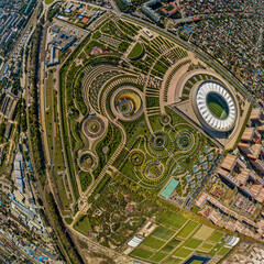 Fototapeta na wymiar urban regular park on the northeastern outskirts of the city of Krasnodar and a snow-white stadium. Aerial panorama on a sunny day in early autumn