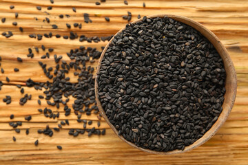 Bowl of black sesame seeds on wooden background, closeup