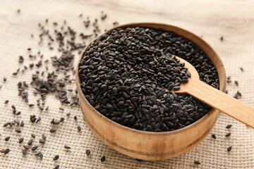 Wooden bowl of black sesame seeds on table, closeup