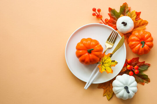 Autumn table setting. White plate, golden cutlery and fall decorations. Flat lay image with copy space.