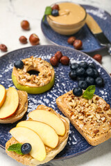 Plate of tasty sandwiches with nut butter, apples and blueberry on light background, closeup