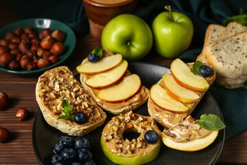 Plate of tasty sandwiches with nut butter and apples on wooden table, closeup