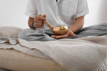 Young man with Tibetan singing bowl at home