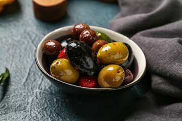 Bowl of different delicious olives on dark color background, closeup