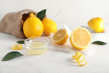 Fresh lemons and bowl of juice on light background