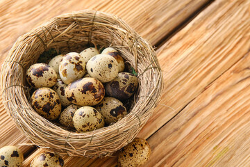 Nest of fresh quail eggs on wooden table, closeup