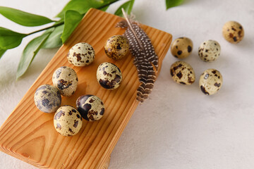 Wooden board with fresh quail eggs on light background, closeup