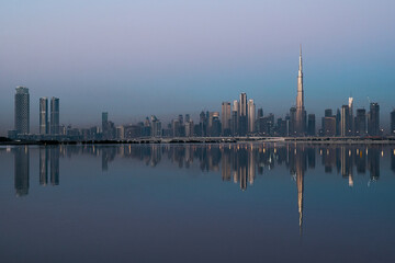 Dubai city skyline reflecting on the water surface during sunset