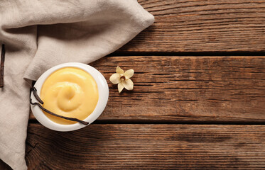 Ramekin of tasty vanilla pudding on wooden background