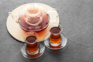Glass cups of hot black tea on dark background