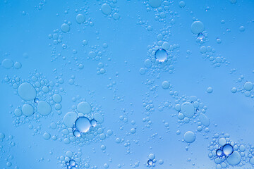 Oil and water bubbles on blue background. Abstract face cleanser bubbles background.