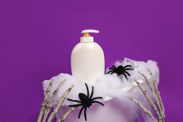 Cosmetic bottle with soap or body lotion staying in the bath with halloween decor skeleton hands...