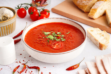 Bowl of delicious tomato soup on light background