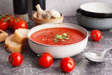 Bowl of tasty tomato soup and bread on grunge background
