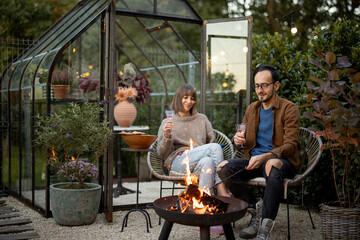 Young couple have a dinner by the fire at backyard