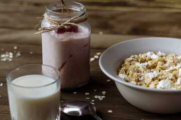 Delicious healthy breakfast: strawberries and cherries in yogurt, oatmeal in a plate, milk in a glass,  close-up. Concept of healthy food and diet