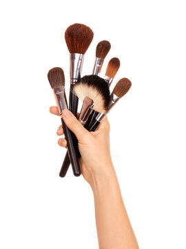 Makeup artist's hand holds professional natural makeup brushes. Isolated on white background. A set of brushes of different shapes for creating makeup