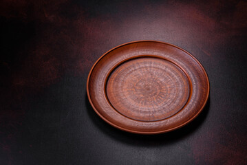 An empty brown ceramic plate on a dark concrete brown background