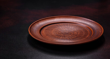 An empty brown ceramic plate on a dark concrete brown background