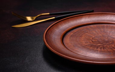 An empty brown ceramic plate on a dark concrete brown background
