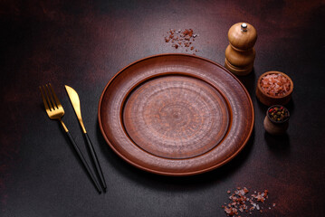 An empty brown ceramic plate on a dark concrete brown background