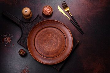 An empty brown ceramic plate on a dark concrete brown background