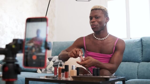 Transgender beauty blogger applying makeup to mobile phone camera