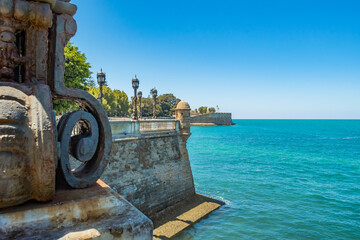 Metal blur of street lamp on stone wall of bastion de la Candelaria flanked by Atlantic Ocean,...