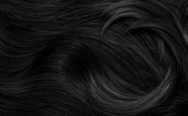 Brunette or black hair. Female long dark hair in black. Beautifully laid curls. Closeup texture in a dark key. Hairdressing, hair care and coloring. Shading gray hair. Background with copy space.