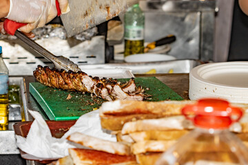 Unrecognizable cook cutting barbecued ribs with a steak knife at the central market in Buenos Aires...