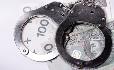 Police handcuffs and banknotes in Polish currency. The concept of economic crime in Poland. Banknotes of Polish zlotys.