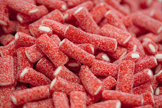 Red gummies jelly candies in sugar, background.