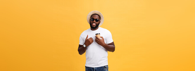 Fototapeta na wymiar Stylish young african american man holding cup of take away coffee isolated over yellow background.