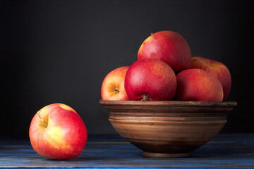 Fototapeta na wymiar Ripe red apples in earthenware bowl on a dark blue background