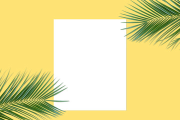 White blank sheet and palm leaves on yellow background