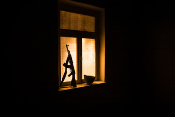 Conceptual photo of war between Russia and Ukraine. Ukraine and Russia flags on windowsill at night. Old creepy room with window.