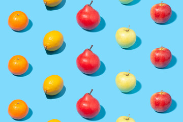 Ripe yellow apricots, apples, lemons and pears on light blue background - creative summer pattern