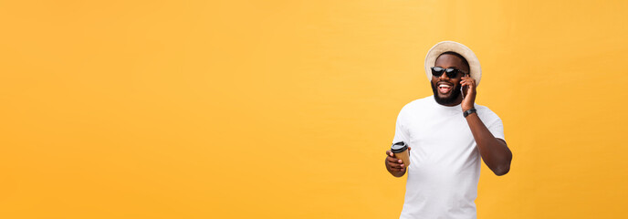 Fototapeta na wymiar Handsome African American with mobile phone and take away coffee cup. Isolated over yellow gold background.