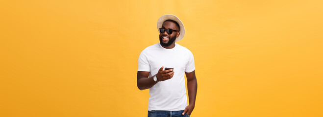 Fototapeta na wymiar Cheerful African American man in white shirt using mobile phone application. happy dark skinned hipster guy read news from social network in mobile phone.